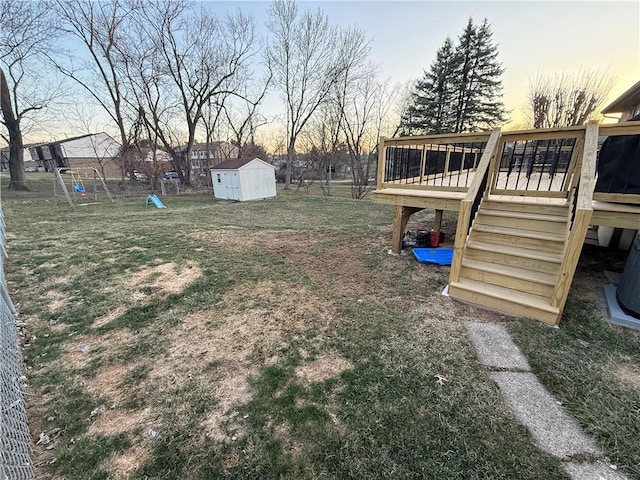 view of yard with stairway, a shed, a wooden deck, an outdoor structure, and a playground