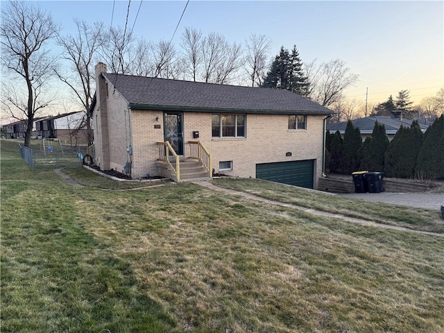 view of front of house featuring brick siding, a front yard, a chimney, a garage, and driveway