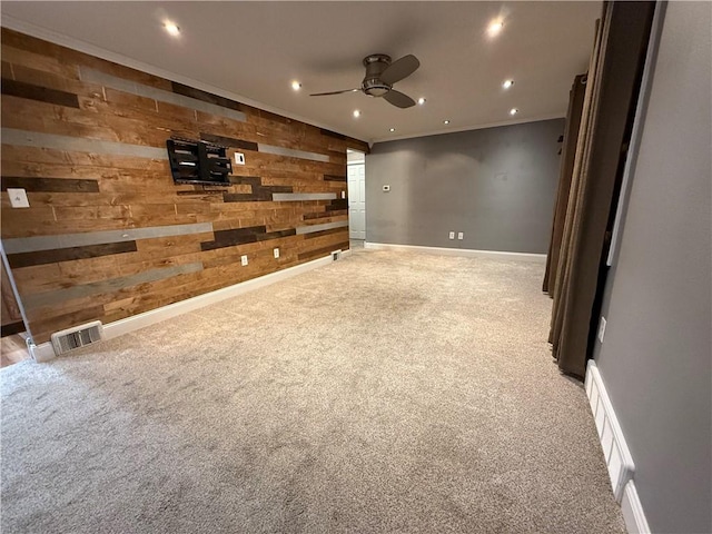 carpeted empty room with visible vents, recessed lighting, baseboards, and wooden walls