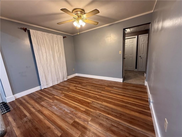 empty room featuring crown molding, baseboards, ceiling fan, attic access, and wood finished floors