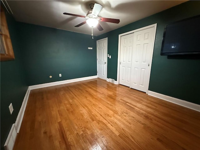 unfurnished bedroom featuring baseboards, light wood-style flooring, and a ceiling fan