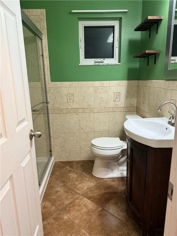 bathroom featuring a shower stall, vanity, tile walls, and toilet