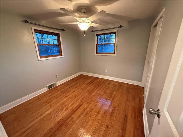 unfurnished bedroom with a closet, visible vents, baseboards, and wood finished floors