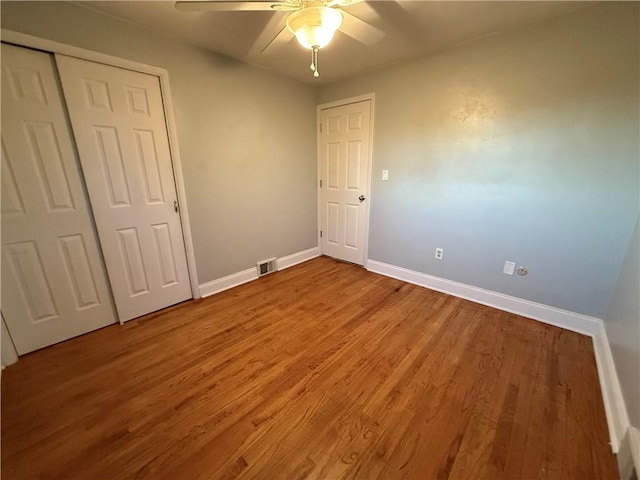 unfurnished bedroom featuring a closet, a ceiling fan, baseboards, and wood finished floors