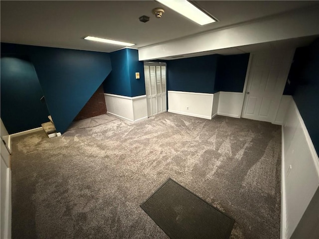 finished below grade area featuring carpet flooring and a wainscoted wall