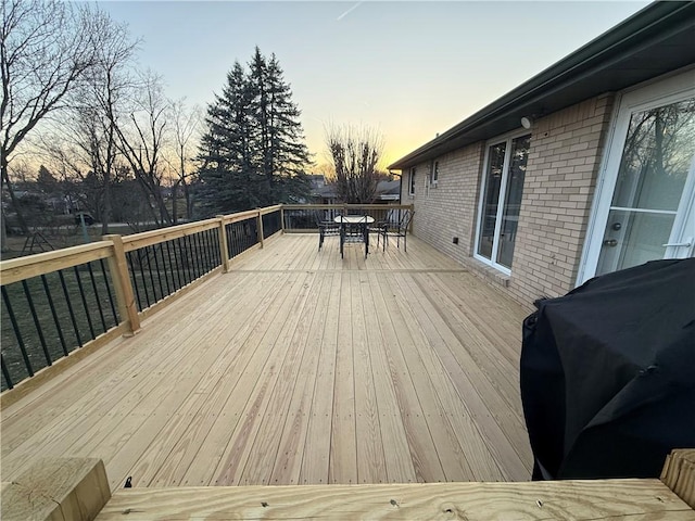 deck at dusk featuring outdoor dining space and grilling area