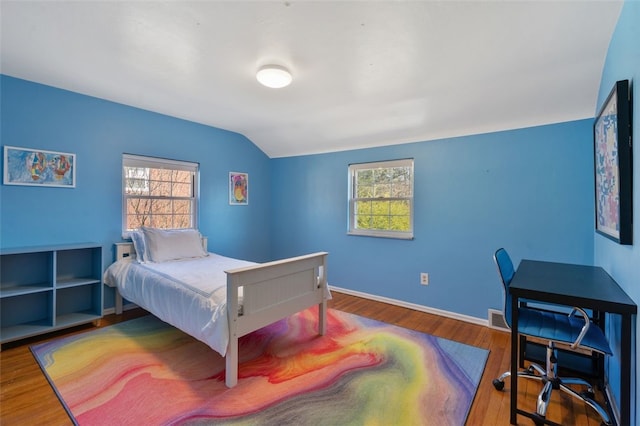 bedroom featuring visible vents, multiple windows, wood finished floors, and vaulted ceiling