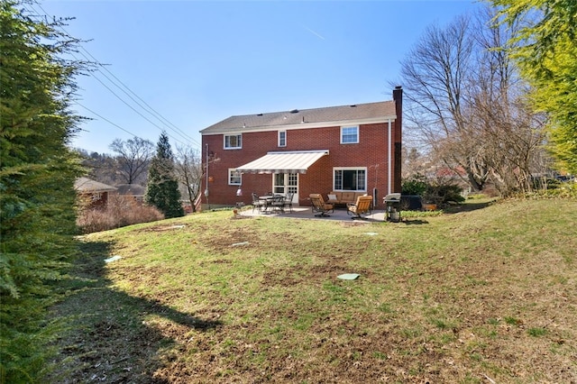 rear view of property featuring brick siding, a patio, a lawn, and a chimney