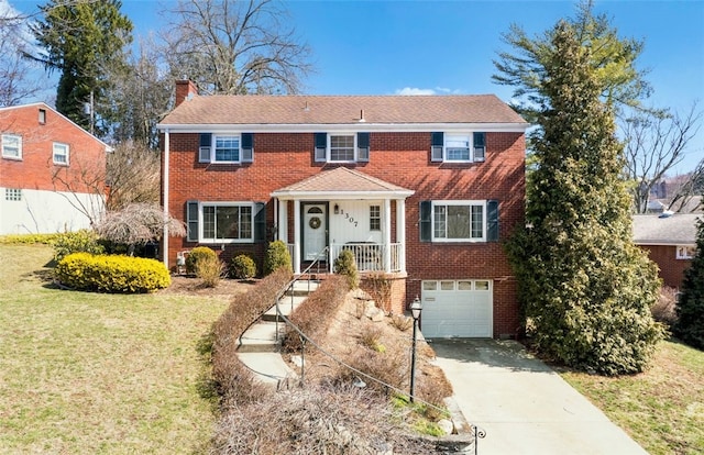 colonial home with a garage, a front lawn, brick siding, and a chimney