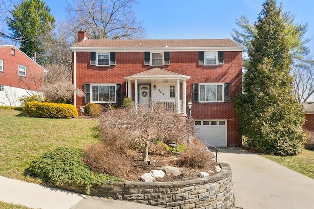 colonial house featuring brick siding, concrete driveway, a chimney, and a garage