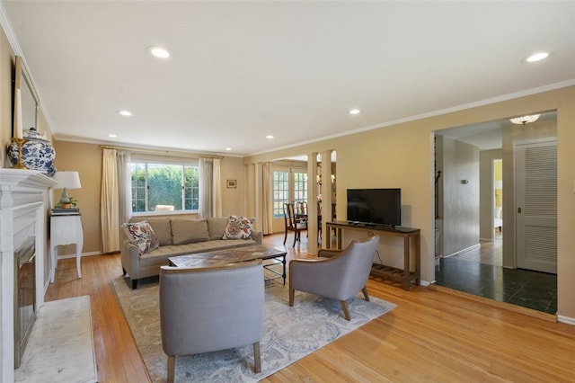 living room with a high end fireplace, baseboards, ornamental molding, recessed lighting, and wood finished floors