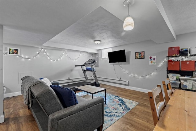 living area with a baseboard heating unit, baseboards, and wood finished floors