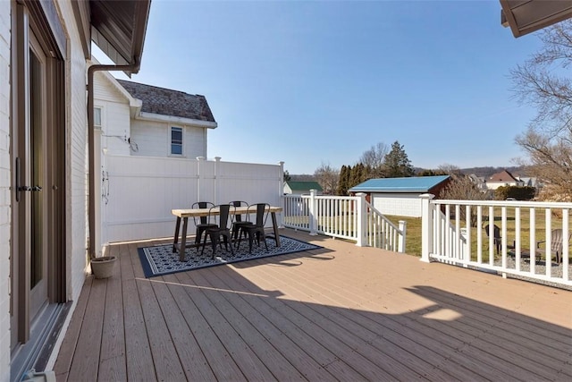 deck with a shed, outdoor dining area, and an outdoor structure