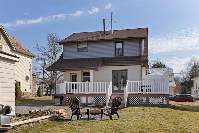 rear view of property with a fire pit, a yard, and roof with shingles