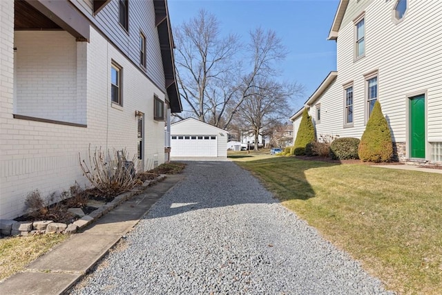 view of side of property with an outdoor structure, a garage, a lawn, and brick siding