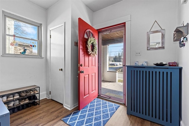 foyer featuring baseboards, wood finished floors, and radiator heating unit