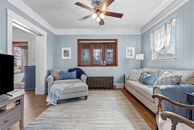 living room featuring a ceiling fan, radiator heating unit, and wood finished floors