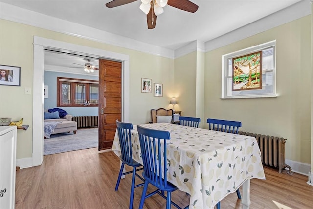 dining room with baseboards, radiator, wood finished floors, and ornamental molding