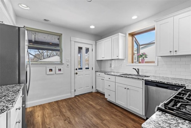 kitchen featuring dark wood-style floors, a healthy amount of sunlight, light stone countertops, and a sink