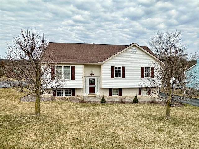 raised ranch with roof with shingles and a front lawn