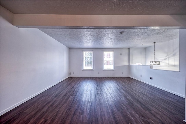 spare room featuring baseboards, a textured ceiling, and dark wood-style flooring