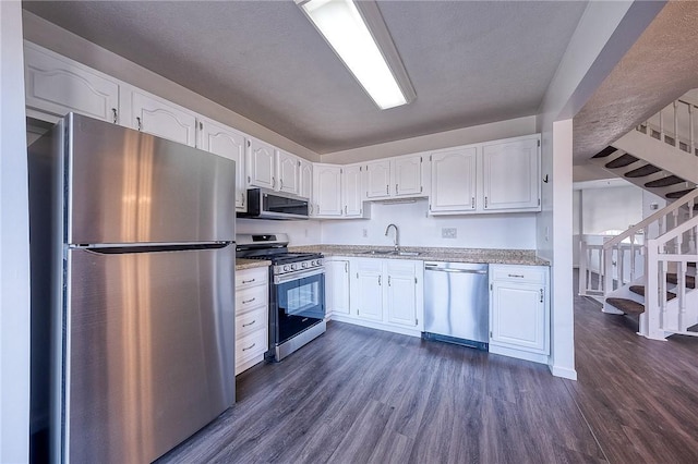 kitchen with a sink, stainless steel appliances, dark wood-type flooring, and white cabinetry