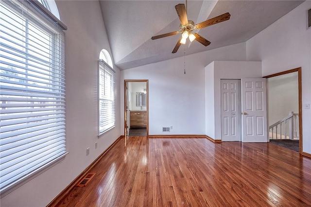 unfurnished bedroom with visible vents, high vaulted ceiling, baseboards, and hardwood / wood-style flooring