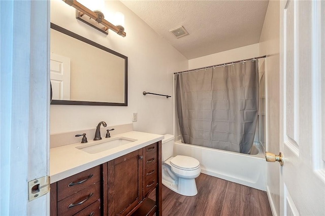 bathroom with visible vents, toilet, a textured ceiling, wood finished floors, and vanity