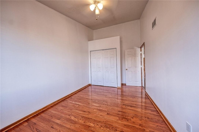 unfurnished bedroom featuring visible vents, ceiling fan, baseboards, wood finished floors, and a closet