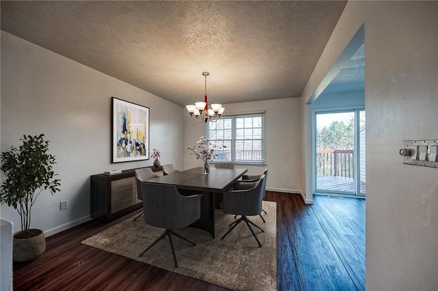 dining room featuring dark wood-style floors, a textured ceiling, baseboards, and an inviting chandelier