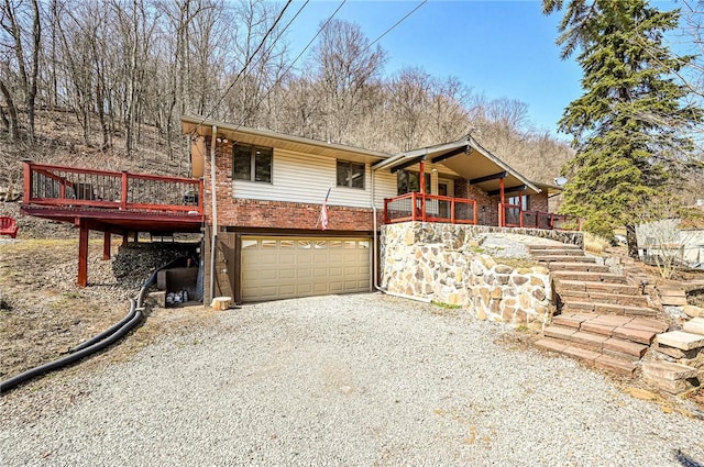 view of front of home with brick siding, stairway, a garage, a deck, and driveway