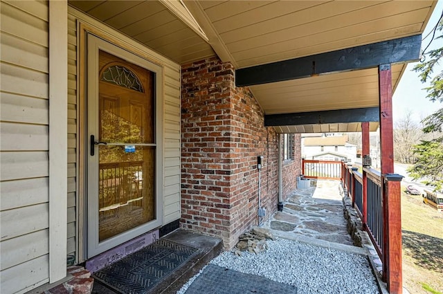 doorway to property with brick siding and covered porch