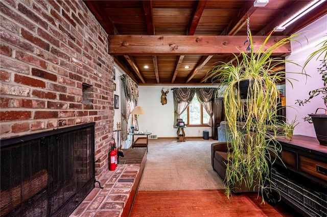 carpeted living room with beam ceiling, a brick fireplace, wood ceiling, and baseboards