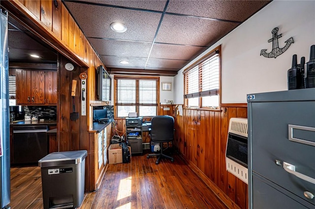 office space featuring a wainscoted wall, dark wood-type flooring, heating unit, wooden walls, and a paneled ceiling