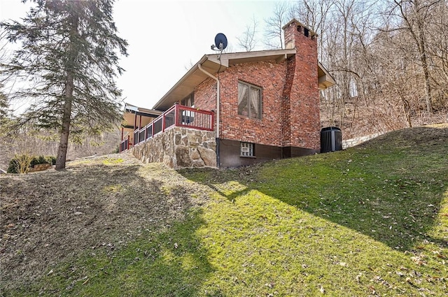 view of home's exterior with stairway, a lawn, brick siding, and a chimney