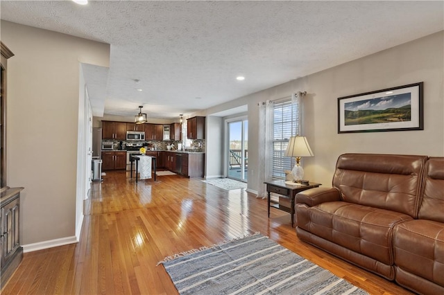 living room featuring recessed lighting, a textured ceiling, baseboards, and hardwood / wood-style floors