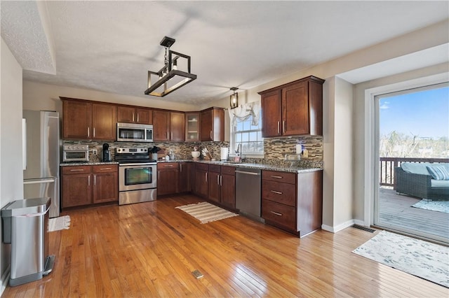 kitchen featuring a sink, decorative backsplash, light wood-style flooring, and stainless steel appliances