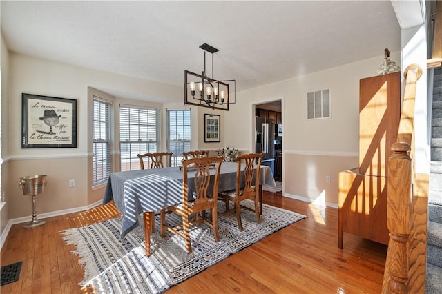 dining space featuring an inviting chandelier, stairway, light wood-style flooring, and visible vents