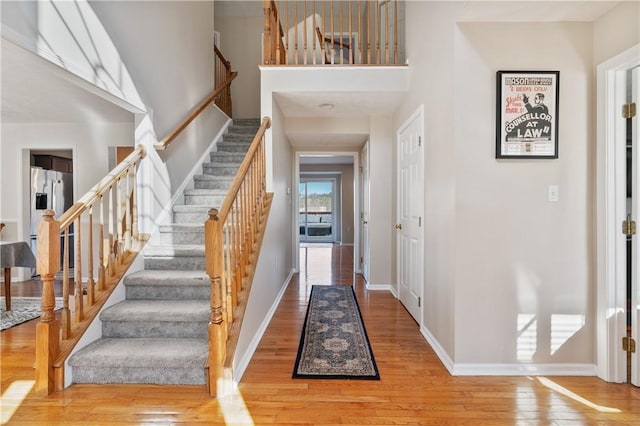 entrance foyer with stairs, baseboards, hardwood / wood-style floors, and a towering ceiling