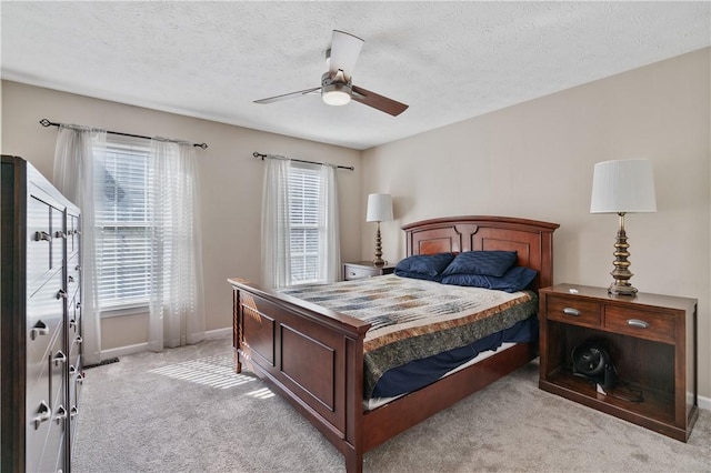 bedroom featuring a ceiling fan, light colored carpet, baseboards, and a textured ceiling