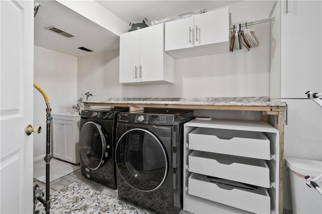 laundry area with cabinet space, washing machine and dryer, and visible vents