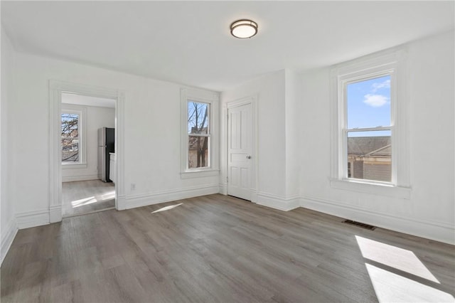 spare room featuring visible vents, baseboards, and wood finished floors