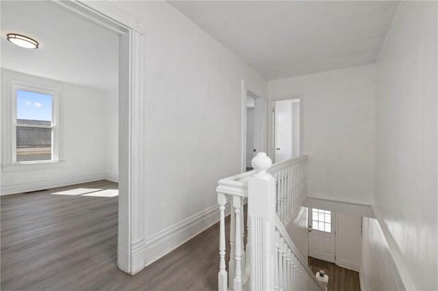 hallway featuring wood finished floors, an upstairs landing, baseboards, and a wealth of natural light