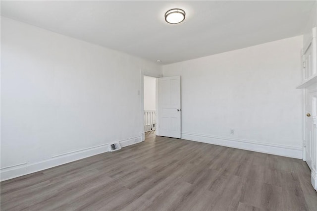 unfurnished room featuring visible vents, baseboards, and wood finished floors