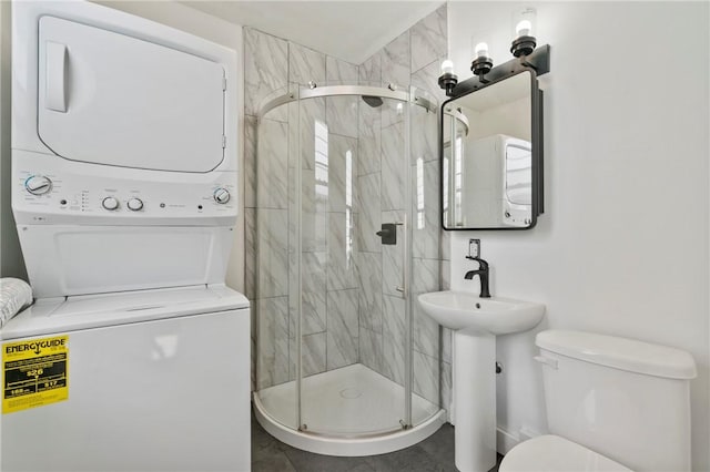 bathroom featuring a sink, toilet, a shower stall, and stacked washer / dryer