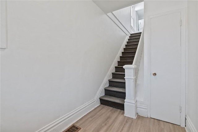 staircase featuring wood finished floors and baseboards