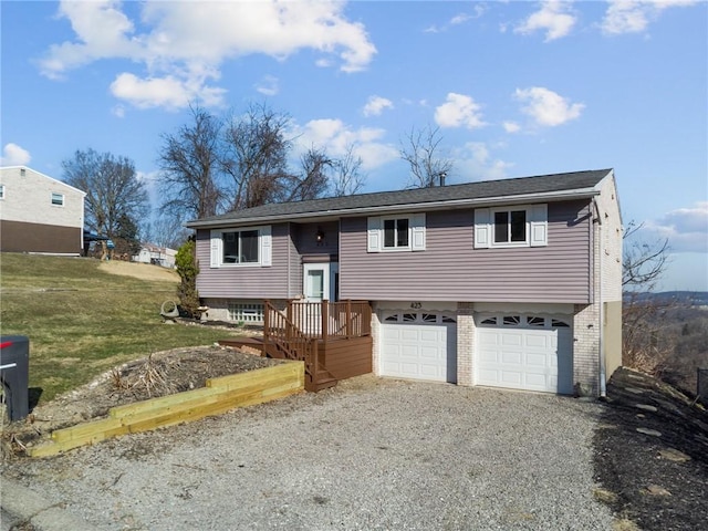 split foyer home featuring gravel driveway, a front yard, an attached garage, and brick siding