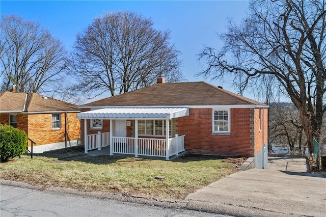 bungalow-style home featuring brick siding, covered porch, a chimney, and a front lawn