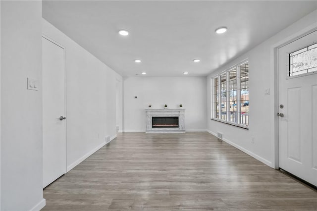 unfurnished living room with visible vents, recessed lighting, wood finished floors, and a premium fireplace