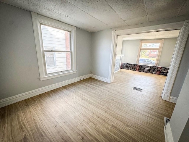 spare room featuring visible vents, a paneled ceiling, baseboards, and wood finished floors